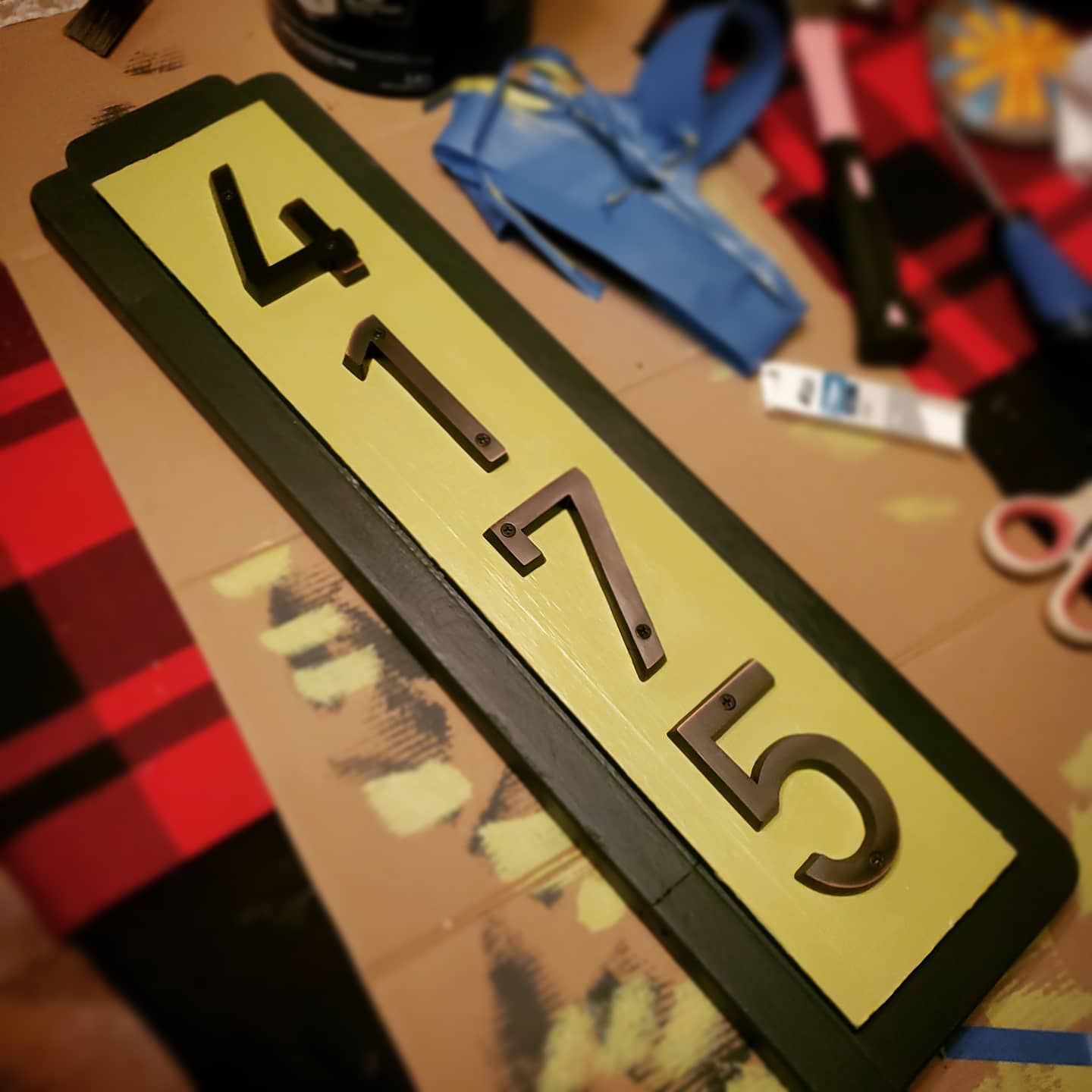 A photo of a house number sign after being painted, laying on a piece of cardboard