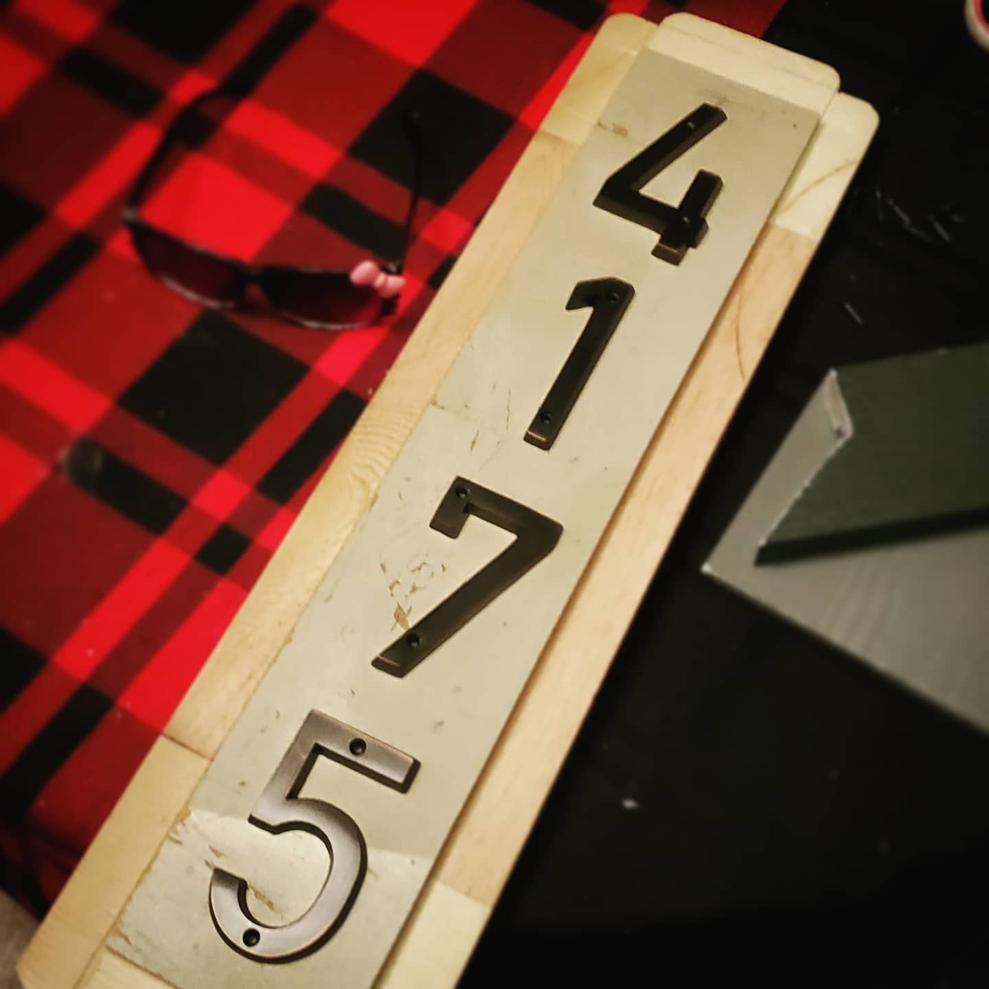 A photo of a house number sign in process of being constructed, but not painted