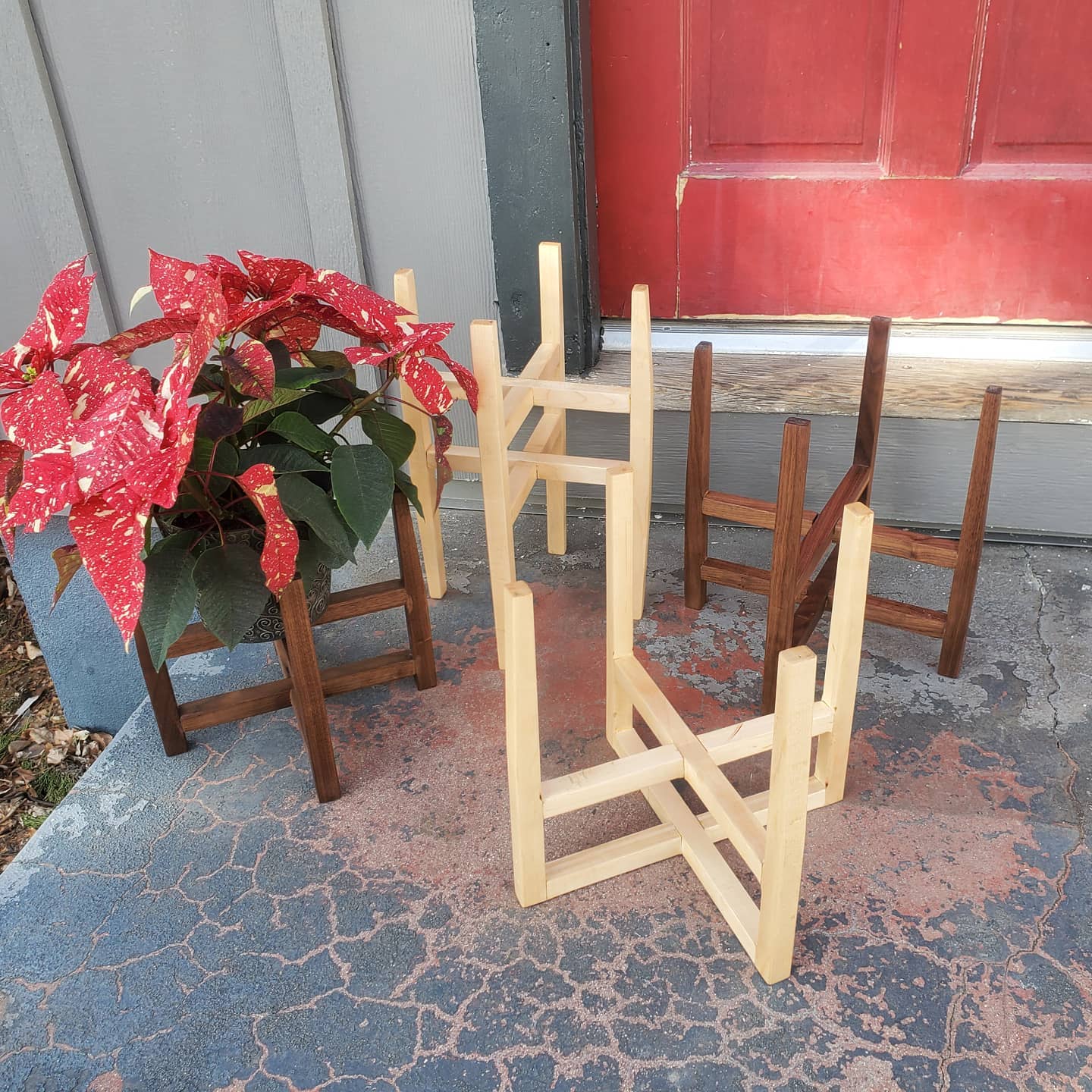 4 mid-mod style plant stands made out of Maple or Walnut sitting on a cement porch