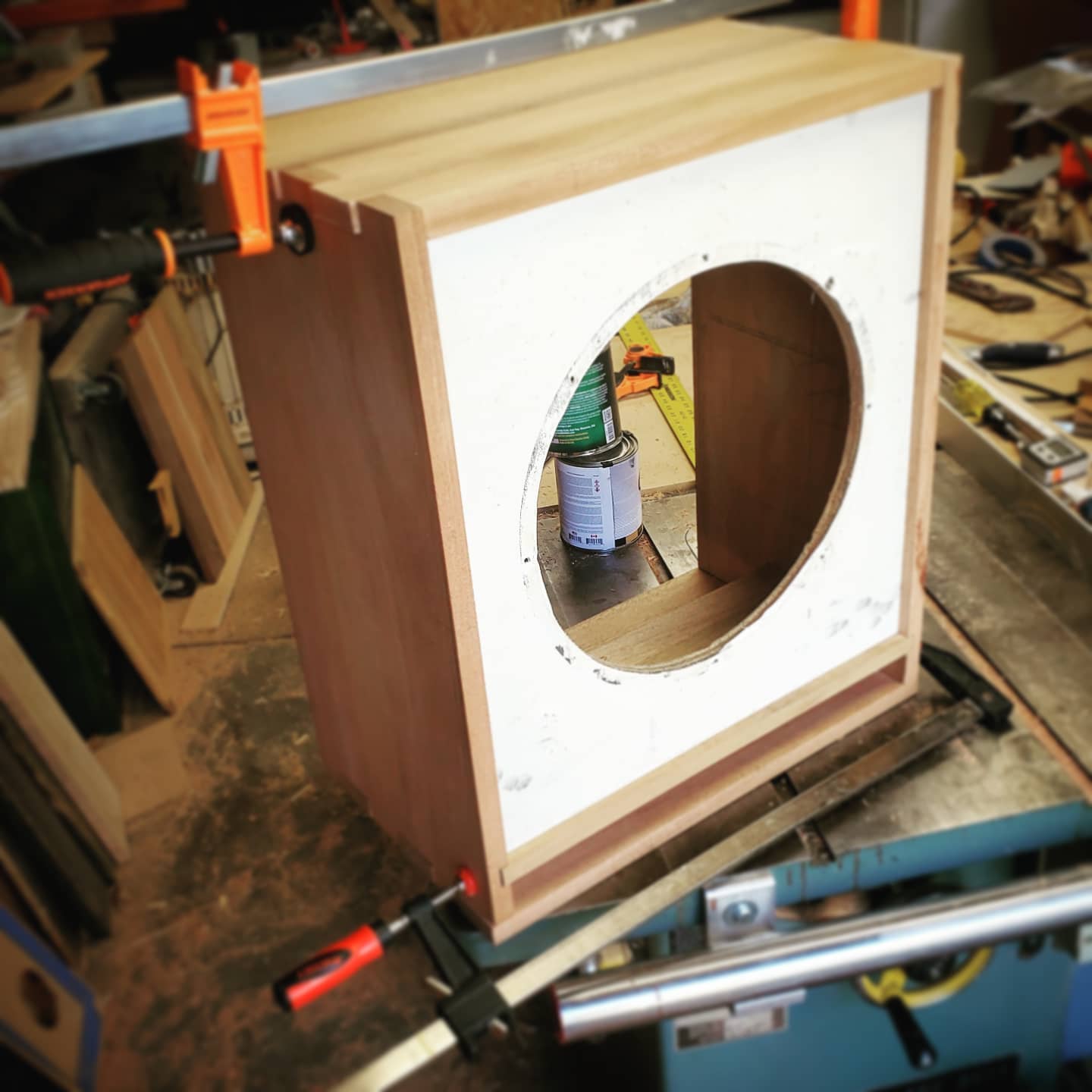a bass speaker cabinet in construction process with a white speaker baffle.