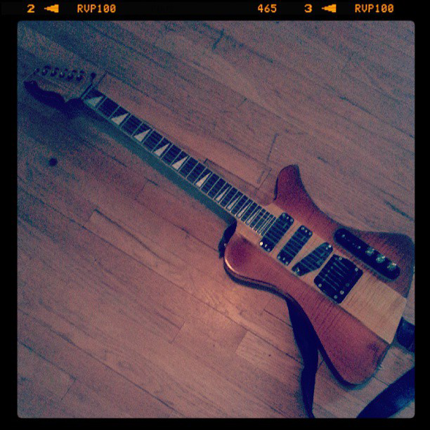 An image of Josie Cool Guitar Works #006, an angular electric guitar, laying on a wood floor.